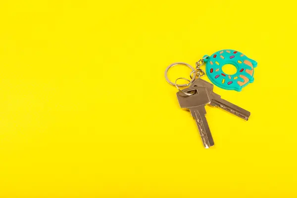 Keychain in the shape of a donut with a key ring on a yellow background. Concepts for real estate and moving home or renting property. Buying a property. Mock-up keychain.Copy space.