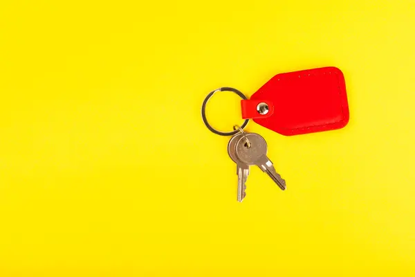 Leather keychain with a key ring on a yellow background. Concepts for real estate and moving home or renting property. Buying a property. Mock-up keychain.Copy space.