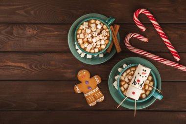 Şekerlemeli sıcak içecek ve şeker kamışı bir dokuma masasında. Sıcak mevsimlik tatiller. Zencefilli Noel kurabiyeleriyle sıcak kakao. Şekerlemeli ve baharatlı sıcak çikolata..