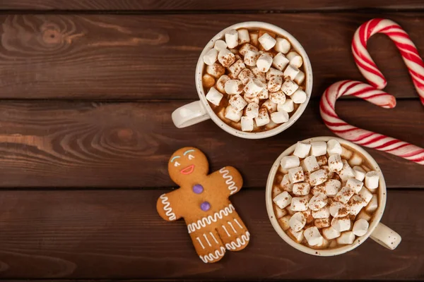 Hot drink with marshmallows and candy cane in  cup on a texture table.Cozy seasonal holidays.Hot cocoa with gingerbread Christmas cookies.Hot chocolate with marshmallow and spices.Copy space.