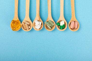 Vitaminler ve takviyeler. Ahşap kaşıklardaki vitamin tabletlerinin dokulu arka planda çeşitliliği. Her gün için multivitamin kompleksi. Besleyici takviyeler. Boşluğu kopyala. Bağışıklık için vitaminler.