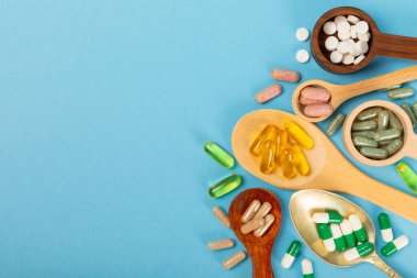 Vitaminler ve takviyeler. Ahşap kaşıklardaki vitamin tabletlerinin dokulu arka planda çeşitliliği. Her gün için multivitamin kompleksi. Besleyici takviyeler. Boşluğu kopyala. Bağışıklık için vitaminler.