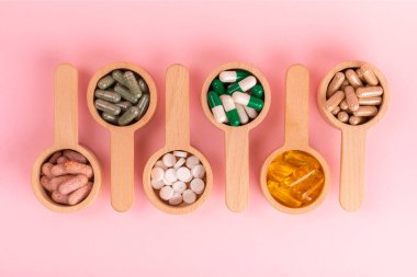 Vitaminler ve takviyeler. Ahşap kaşıklardaki vitamin tabletlerinin dokulu arka planda çeşitliliği. Her gün için multivitamin kompleksi. Besleyici takviyeler. Boşluğu kopyala. Bağışıklık için vitaminler.