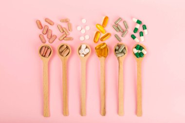 Vitaminler ve takviyeler. Ahşap kaşıklardaki vitamin tabletlerinin dokulu arka planda çeşitliliği. Her gün için multivitamin kompleksi. Besleyici takviyeler. Boşluğu kopyala. Bağışıklık için vitaminler.