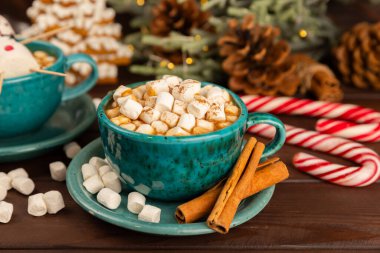Şekerlemeli sıcak içecek ve desenli masa üzerinde şeker kamışı. Sıcak mevsimlik tatiller. Zencefilli Noel kurabiyeleriyle sıcak kakao. Marşmelov ve baharatla sıcak çikolata..