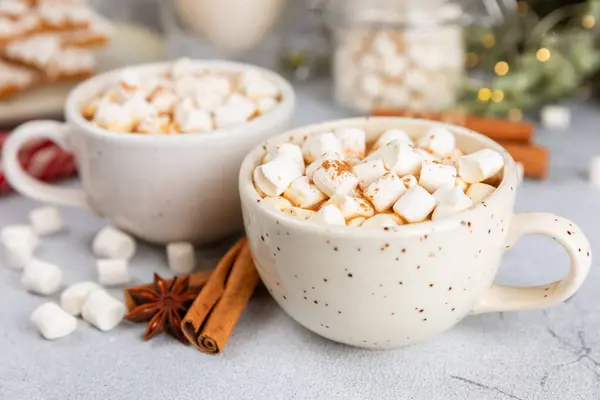 Hot drink with marshmallows and candy cane in cup on texture table.Cozy seasonal holidays.Hot cocoa with gingerbread Christmas cookies.Hot chocolate with marshmallow and spices.Copy space.