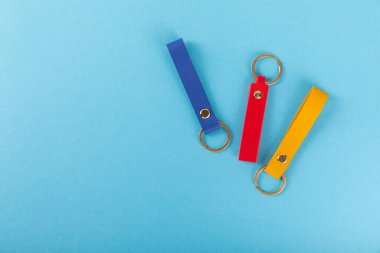 Mavi arka planda anahtarlığı olan deri bir anahtarlık. Gayrimenkul ve eve taşınma ya da mülk kiralama kavramları. Mülk almak. Model anahtarlık. Boşluğu kopyala.