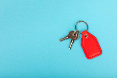Mavi arka planda anahtarlığı olan deri bir anahtarlık. Gayrimenkul ve eve taşınma ya da mülk kiralama kavramları. Mülk almak. Model anahtarlık. Boşluğu kopyala.