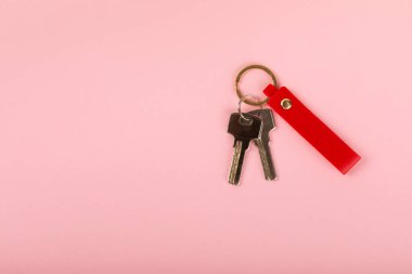 Pembe arka planda anahtarlığı olan deri bir anahtarlık. Gayrimenkul ve eve taşınma ya da mülk kiralama kavramları. Mülk almak. Model anahtarlık. Boşluğu kopyala.