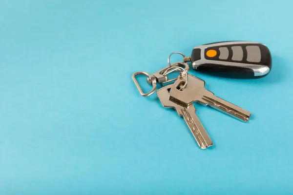 Car key with key fob on a colored background. Buying or renting a car. Car gift. Stylish keychain with car key. Place for text. Copy space.
