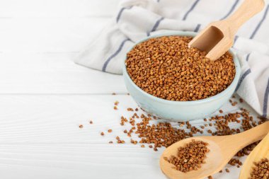 Beyaz ahşap arka planda bir kasede karabuğday lapası. Sağlıklı yiyecekler. Diyet olsun. Organik mısır gevreği. Çiğ karabuğday. Sağlıklı beslenme için glütensiz kadim tahıl. Mesaj için yer. Boşluğu kopyala.