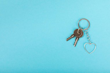 Kalp şeklinde anahtarlık, anahtarlık iyonu renkli bir arka plan. Gayrimenkul ve eve taşınma ya da mülk kiralama kavramları. Mülk almak. Model anahtarlık. Boşluğu kopyala.