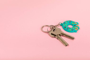 Donut şekilli anahtarlık ve renkli bir arka planda anahtarlık. Gayrimenkul ve eve taşınma ya da mülk kiralama kavramları. Mülk almak. Model anahtarlık. Boşluğu kopyala.