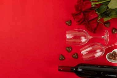 Sevgililer Günü konsepti. Sevgililer Günü geçmişi. Hediyeler, mumlar, konfeti, zarf - kartpostal, şeker, bardak, şarap ve kırmızı arka planda bir buket gül. Flatley. Sevgililer Günü kutlaması.