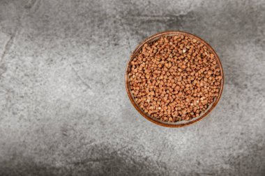 Ahşap kaplamalı bir kasede çiğ karabuğday. Buğday taneleri, yulaf lapası, tahıllar, tabakta çiğ karabuğday. Sağlıklı yiyecekler. Yulaf. Diyet olsun. Organik mısır gevreği. Metin için boşluk. Boşluğu kopyala.