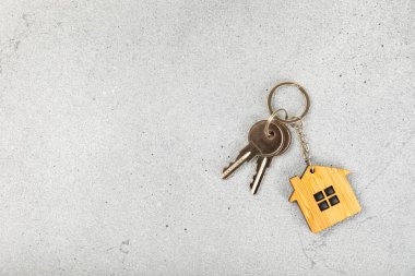 Anahtar zinciri, arka planında anahtarlık olan bir ev şeklinde. Gayrimenkul ve eve taşınma ya da mülk kiralama kavramları. Mülk almak. Model anahtarlık şeklinde ev.