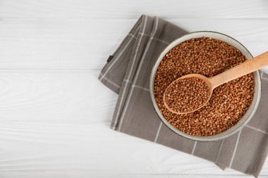 Arka planda desenli bir kasede çiğ karabuğday. Buğday taneleri, yulaf lapası, tahıllar, tabakta çiğ karabuğday. Sağlıklı yiyecekler. Yulaf. Diyet olsun. Organik mısır gevreği. Metin için boşluk. Boşluğu kopyala.