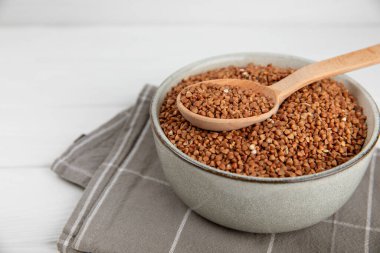 Arka planda desenli bir kasede çiğ karabuğday. Buğday taneleri, yulaf lapası, tahıllar, tabakta çiğ karabuğday. Sağlıklı yiyecekler. Yulaf. Diyet olsun. Organik mısır gevreği. Metin için boşluk. Boşluğu kopyala.