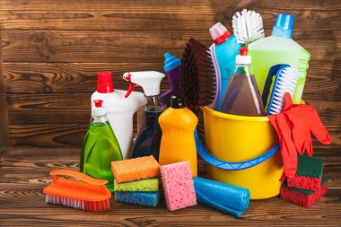 Temizlik hizmeti konsepti. Ahşap arka planda ev temizlik ürünü. Evdeki kimyasallarla dolu bir kova. Ev ve ofis için temizlik malzemeleri. Erken bahar düzenli temizlik. Boşluğu kopyala