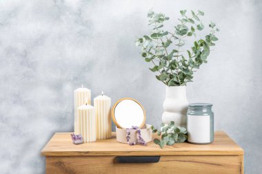 Yeşil okaliptüs, bir vazo tezgahında, çekmecelerden oluşan bir sandıkta duvarın arka planında durur. Aromaterapi. Çok güzel bir okaliptüs buketi. Çiçekler, mumlar ve aroma yayıcı ile minimalist iç mekan..