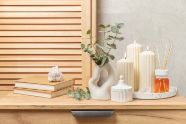 Yeşil okaliptüs, bir vazo tezgahında, çekmecelerden oluşan bir sandıkta duvarın arka planında durur. Aromaterapi. Çok güzel bir okaliptüs buketi. Çiçekler, mumlar ve aroma yayıcı ile minimalist iç mekan..