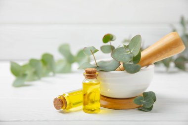 Tahta zeminde okaliptüs yaprakları ve harç. Alternatif tıp ve doğal kozmetik ürünleri için spa konsepti. Bir şişe gerekli yağ ve bir demet okaliptüs. Organik cilt bakımı 