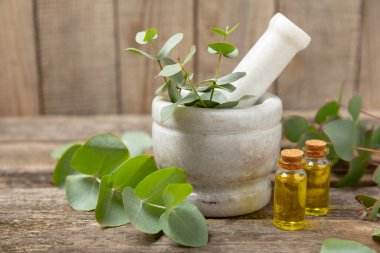 Tahta zeminde okaliptüs yaprakları ve harç. Alternatif tıp ve doğal kozmetik ürünleri için spa konsepti. Bir şişe gerekli yağ ve bir demet okaliptüs. Organik cilt bakımı 