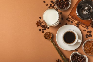 Kahve yapmak için gerekli malzemeler. Kahverengi zemin üzerinde kahve çekirdeği, süt, şeker ve baharat bulunan kahve makinası. İçki hazırlama konsepti. Düz Katman. Boşluğu kopyala.