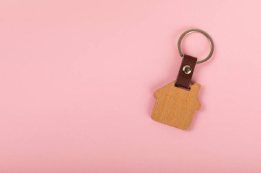 Renkli arka planda ev şeklinde anahtarlığı olan ev anahtarları. Tasarım elemanı. Emlak ve sigorta konsepti. Emlak kiralama, satma veya satın alma.