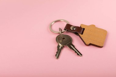Renkli arka planda ev şeklinde anahtarlığı olan ev anahtarları. Tasarım elemanı. Emlak ve sigorta konsepti. Emlak kiralama, satma veya satın alma.