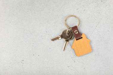 Renkli arka planda ev şeklinde anahtarlığı olan ev anahtarları. Tasarım elemanı. Emlak ve sigorta konsepti. Emlak kiralama, satma veya satın alma.