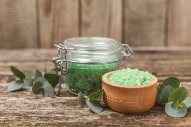 Kozmetik deniz tuzu aromalı ve okaliptüs özlü taze aromatik okaliptüs dallı ahşap bir arkaplan. Spa konsepti. Banyo tuzu. Yakın plan. Metin için boşluk. Vücut bakımı. Boşluğu kopyala