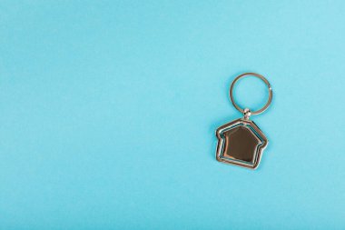 Arka planda anahtarlık olan ev şeklinde anahtarlık. Gayrimenkul ve eve taşınma ya da mülk kiralama kavramları. Mülk almak. Model anahtarlık evi şekillendirildi. Boşluğu kopyala.