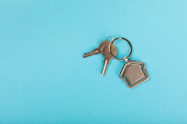 Arka planda anahtarlık olan ev şeklinde anahtarlık. Gayrimenkul ve eve taşınma ya da mülk kiralama kavramları. Mülk almak. Model anahtarlık evi şekillendirildi. Boşluğu kopyala.