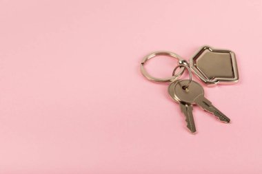 Arka planda anahtarlık olan ev şeklinde anahtarlık. Gayrimenkul ve eve taşınma ya da mülk kiralama kavramları. Mülk almak. Model anahtarlık evi şekillendirildi. Boşluğu kopyala.