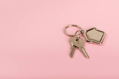 Arka planda anahtarlık olan ev şeklinde anahtarlık. Gayrimenkul ve eve taşınma ya da mülk kiralama kavramları. Mülk almak. Model anahtarlık evi şekillendirildi. Boşluğu kopyala.