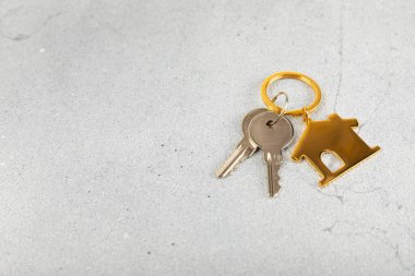 Arka planda anahtarlık olan ev şeklinde anahtarlık. Gayrimenkul ve eve taşınma ya da mülk kiralama kavramları. Mülk almak. Model anahtarlık evi şekillendirildi. Boşluğu kopyala.