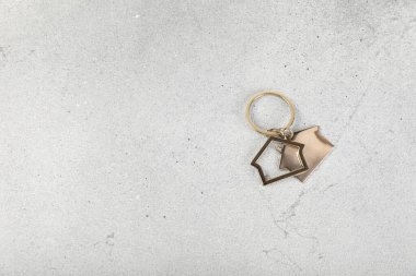 Arka planda anahtarlık olan ev şeklinde anahtarlık. Gayrimenkul ve eve taşınma ya da mülk kiralama kavramları. Mülk almak. Model anahtarlık evi şekillendirildi. Boşluğu kopyala.