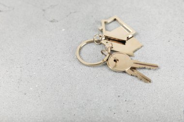 Arka planda anahtarlık olan ev şeklinde anahtarlık. Gayrimenkul ve eve taşınma ya da mülk kiralama kavramları. Mülk almak. Model anahtarlık evi şekillendirildi. Boşluğu kopyala.