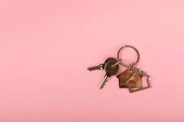 Keychain in the shape of a house with a key ring on background. Concepts for real estate and moving home or renting property. Buying a property. Mock-up keychain house shaped.Copy space.