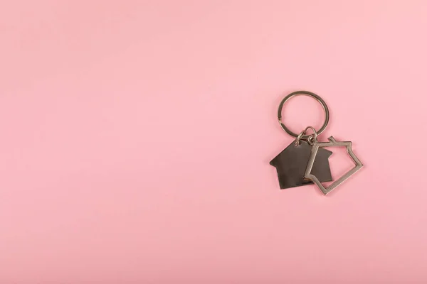 Keychain in the shape of a house with a key ring on background. Concepts for real estate and moving home or renting property. Buying a property. Mock-up keychain house shaped.Copy space.