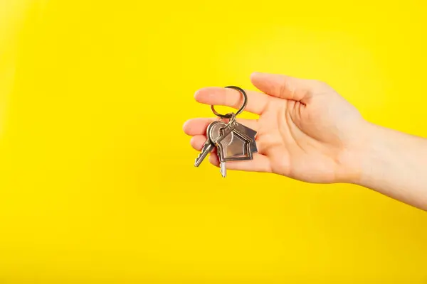 Keychain in the shape of a house with a key ring on background. Concepts for real estate and moving home or renting property. Buying a property. Mock-up keychain house shaped.Copy space.