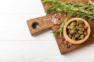 Ahşap mutfak masasında kapari. Deniz tuzu ve biberiyeli kapari. Turşu turşusu. Akdeniz mutfağı malzemesi. Organik baharatlar ve baharatlar. Boşluğu kopyala.