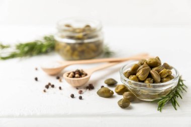 Ahşap mutfak masasında kapari. Deniz tuzu ve biberiyeli kapari. Turşu turşusu. Akdeniz mutfağı malzemesi. Organik baharatlar ve baharatlar. Boşluğu kopyala.