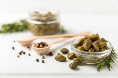 Ahşap mutfak masasında kapari. Deniz tuzu ve biberiyeli kapari. Turşu turşusu. Akdeniz mutfağı malzemesi. Organik baharatlar ve baharatlar. Boşluğu kopyala.