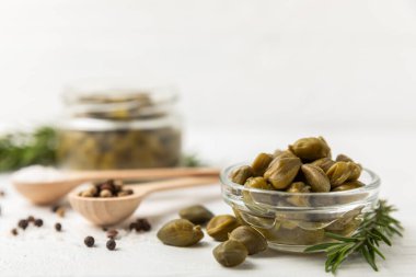 Ahşap mutfak masasında kapari. Deniz tuzu ve biberiyeli kapari. Turşu turşusu. Akdeniz mutfağı malzemesi. Organik baharatlar ve baharatlar. Boşluğu kopyala.