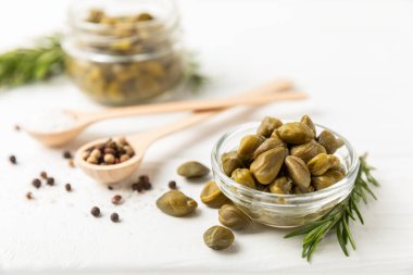 Ahşap mutfak masasında kapari. Deniz tuzu ve biberiyeli kapari. Turşu turşusu. Akdeniz mutfağı malzemesi. Organik baharatlar ve baharatlar. Boşluğu kopyala.