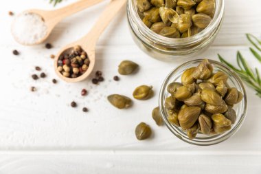 Ahşap mutfak masasında kapari. Deniz tuzu ve biberiyeli kapari. Turşu turşusu. Akdeniz mutfağı malzemesi. Organik baharatlar ve baharatlar. Boşluğu kopyala.