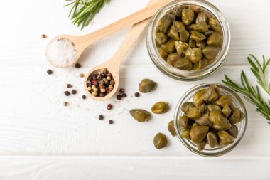 Ahşap mutfak masasında kapari. Deniz tuzu ve biberiyeli kapari. Turşu turşusu. Akdeniz mutfağı malzemesi. Organik baharatlar ve baharatlar. Boşluğu kopyala.