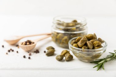 Ahşap mutfak masasında kapari. Deniz tuzu ve biberiyeli kapari. Turşu turşusu. Akdeniz mutfağı malzemesi. Organik baharatlar ve baharatlar. Boşluğu kopyala.